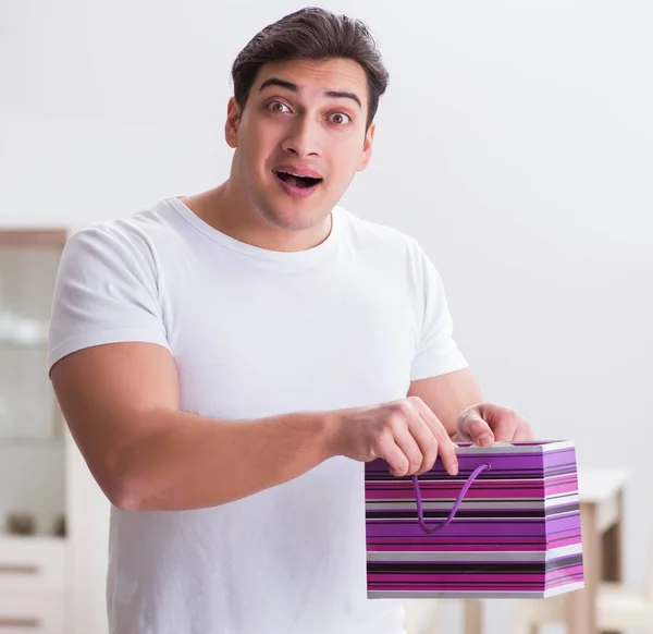 The young man with gift bag at home preparing suprise for wife — Stock Photo, Image