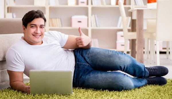 Człowiek pracujący na laptopie w domu na podłodze dywanu — Zdjęcie stockowe