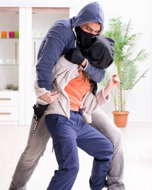 Silahlı adam evde genç bir kadına saldırıyor.