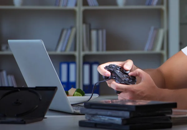 Jovem jogando jogos longas horas atrasado no escritório — Fotografia de Stock