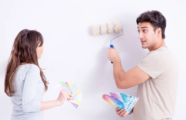 Jovem família fazendo renovação em casa - paredes de pintura — Fotografia de Stock