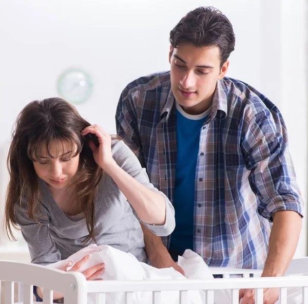 Los padres jóvenes con su bebé recién nacido cerca de la cuna — Foto de Stock