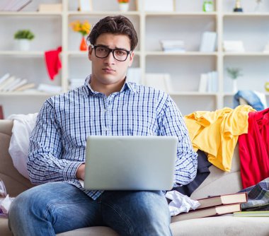 Genç adam dağınık bir odada çalışıyor.