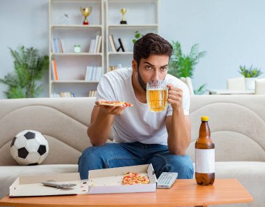 Pizza yiyen adam evde yemek yiyor, dinleniyor.