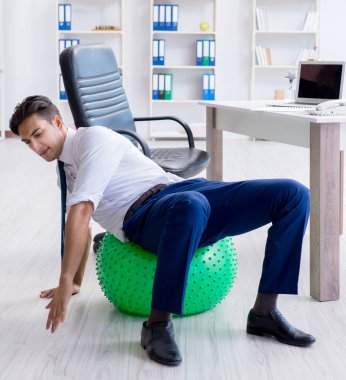 Genç işadamı iş yerinde spor yapıyor.