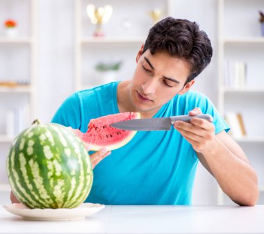 Evde karpuz yiyen bir adam.