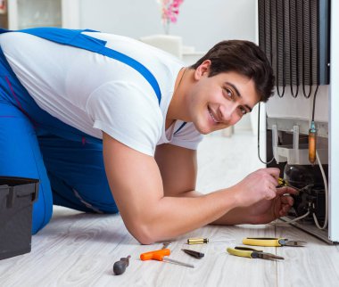 Tamirci müteahhit DIY konseptinde buzdolabını tamir ediyor.