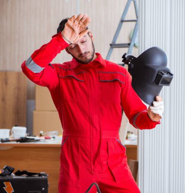 Kaynak tabancası elektrot ve kask takan genç bir tamirci.