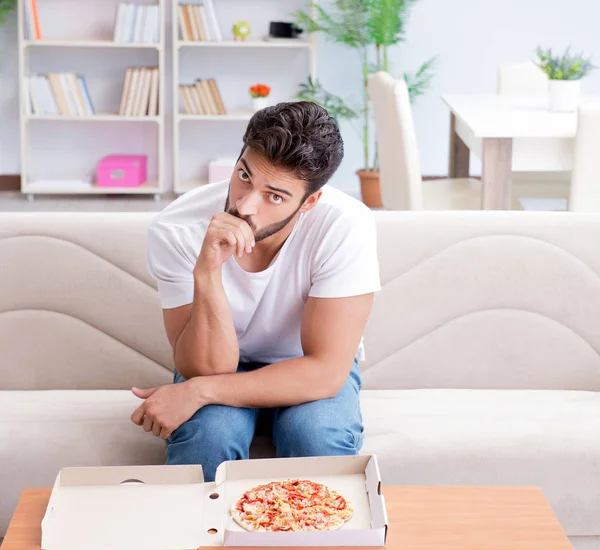 Чоловік їсть піцу, маючи винос вдома розслабляючий відпочинок — стокове фото