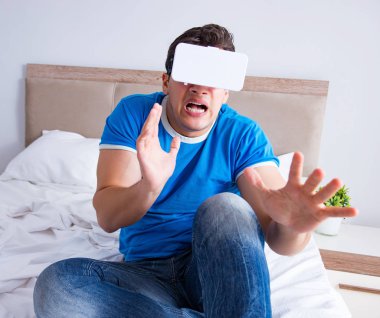 Yatakta sanal gerçeklik başlığı takan genç bir adam.