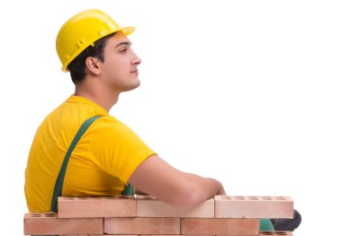 Yakışıklı inşaat işçisi tuğla duvar inşa ediyor.