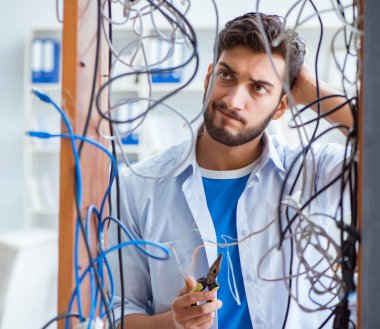 Elektrik teknisyeni tamir konseptinde kabloları çözmeye çalışıyor.