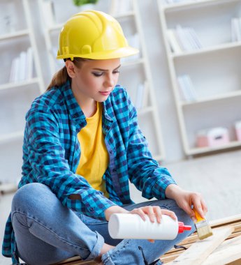 Tamirci kadın marangoz ahşap döşemeleri kesiyor.