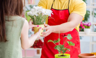 Çiçekçi dükkanında çiçek satıyor.