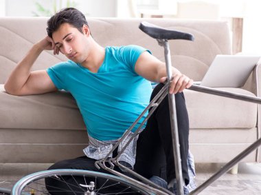 Evde bisiklet tamir eden genç bir adam.