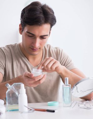 Genç yakışıklı adam aynaya bakıyor.