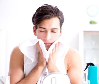 Genç yakışıklı adam aynaya bakıyor.