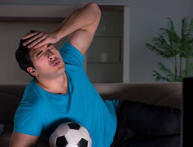 Genç adam gece geç saatlerde futbol seyrediyor.