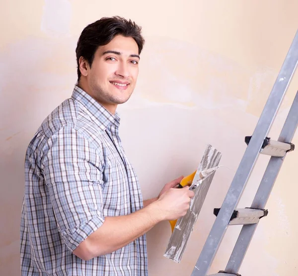 Junger Mann putzt zu Hause Wand auf — Stockfoto