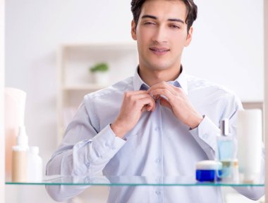 Adam banyoda çalışmak için giyiniyor.