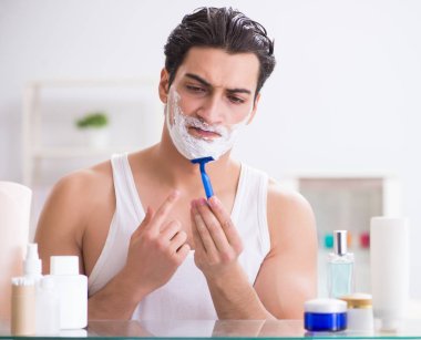 Genç yakışıklı adam sabah erkenden tıraş oluyor.