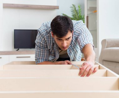 Adam evde mobilya montajı yapıyor.