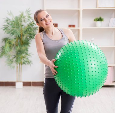 Spor salonunda denge topuyla egzersiz yapan genç bir kadın.