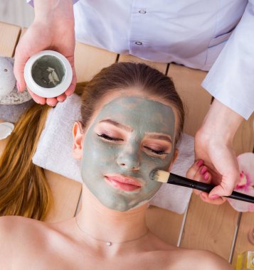 Yüz maskeli, spa sağlık konsepti olan genç bir kadın.