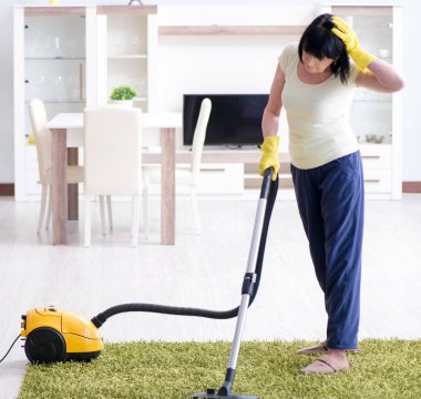 Yaşlı kadın elektrik süpürgesinden yorgun düştü.