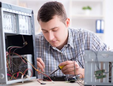 Genç teknisyen atölyede bilgisayar tamir ediyor.