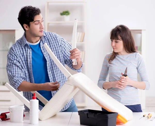 Ehefrau hilft Ehemann, kaputten Stuhl zu Hause zu reparieren — Stockfoto