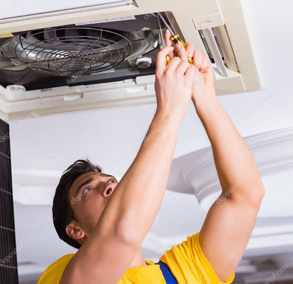 Repairman repairing ceiling air conditioning unit