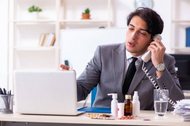 Ofiste grip olmuş bir adam çalışıyor.