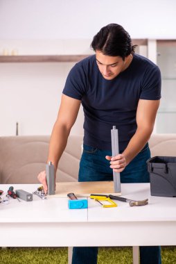 Evdeki mobilyaları tamir eden genç adam.