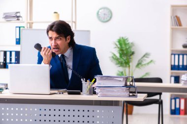 Genç işadamı ofiste oturuyor ve çalışıyor.