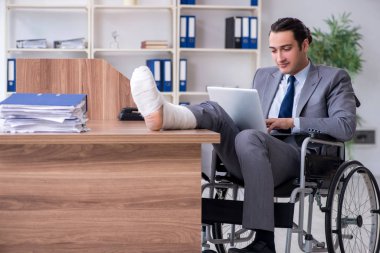 Ofiste tekerlekli sandalyede çalışan bir erkek.