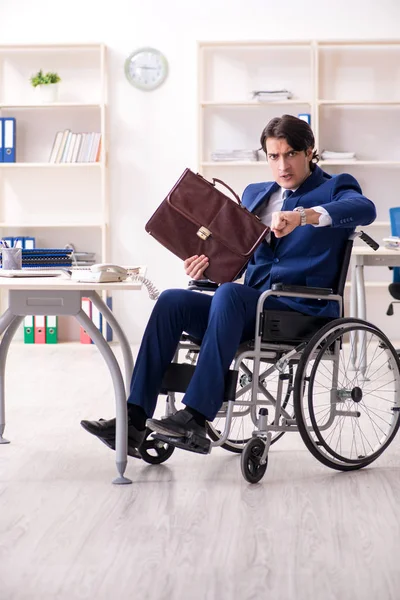 Jonge mannelijke werknemer in een rolstoel in het kantoor — Stockfoto