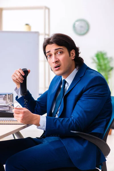 Jeune homme d'affaires assis et travaillant dans le bureau — Photo