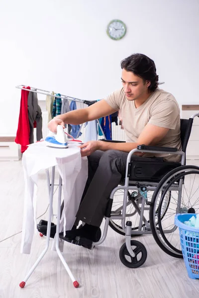 Tekerlekli sandalyedeki genç adam evde ütü yapıyor. — Stok fotoğraf
