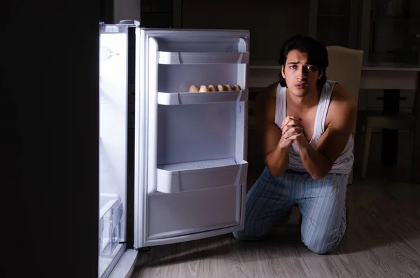 Hombre rompiendo dieta en la noche cerca de la nevera — Foto de Stock