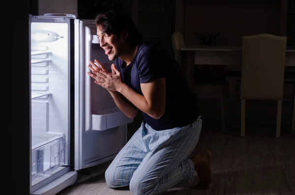 Man bryter diet på natten nära kylskåp — Stockfoto