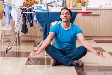 Genç adam evde çamaşır ütülüyor.
