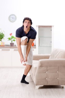 Evde acı çeken bacağı yaralı genç adam.