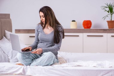 Genç hamile kadın yatak odasında.