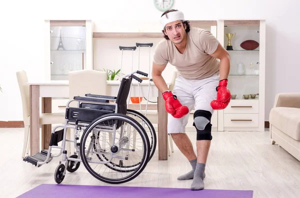 Injured young man doing exercises at home — Stock Photo, Image