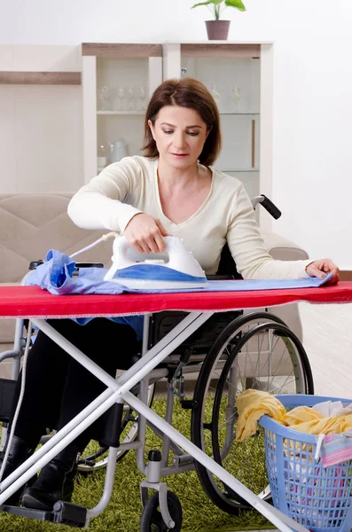 Femme en fauteuil roulant repassage à la maison — Photo