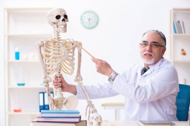 İskeleti olan yaşlı erkek doktor.