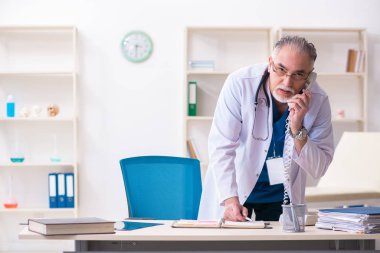 Klinikte çalışan yaşlı erkek doktor.