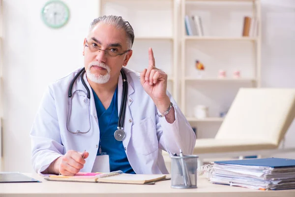 Gammal manlig läkare som arbetar på kliniken — Stockfoto