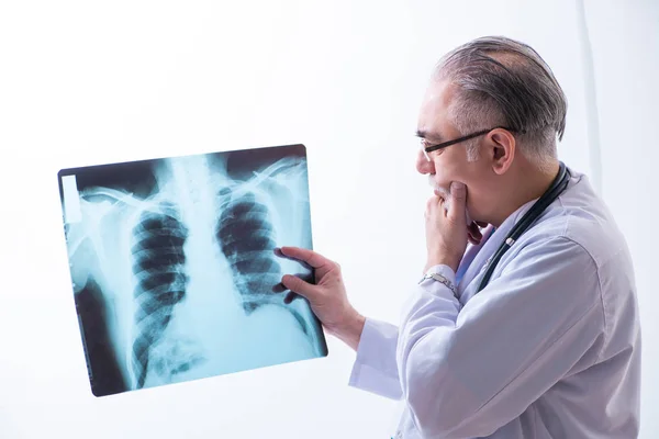 Old male doctor working in the clinic — Stock Photo, Image